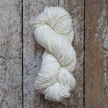 Noro Haunui Silk yarn skein, blend of natural mulberry silk and Haunui merino wool, undyed skien, on rustic wooden background