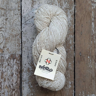 Noro Haunui Silk yarn skein, blend of natural mulberry silk and Haunui merino wool, undyed, on rustic wooden background