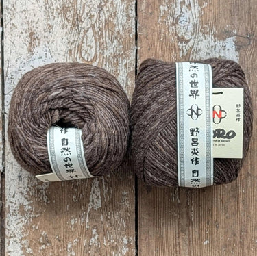 Noro Haunui merino wool barrels from Taranui farm, New Zealand - natural undyed yarn on rustic wooden surface