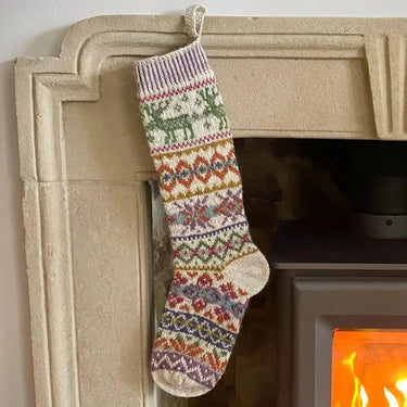 Reindeer Christmas Stocking by Marie Wallin hanging by fireplace, knit festive stockings design, perfect holiday gift for knitters.