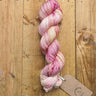 A skein of hand-dyed A&P Classic Sock 4ply yarn in pink hues, perfect for knitting durable and soft socks, hats, and accessories.