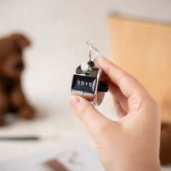 Hand holding stainless steel Row Counter by TOFT for knitting and crochet projects.