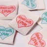 Fabric patches with 'Made with Love' heart text in various colors on a white background.
