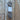 A skein of textured gray yarn with a white paper label, placed vertically on a rustic wooden plank surface with peeling white paint.