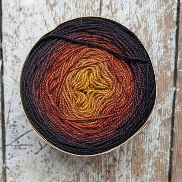 Bilum Snek yarn in gradient hand-dyed merino wool on rustic wood surface