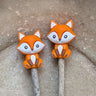 Cute fox Stitch Stoppers from Fox & Pine on knitting needles, preventing stitches from slipping off. Essential knitting accessory.