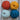 Four balls of yarn in orange, yellow, light blue, and dark blue on a wooden background, perfect for crochet projects.
