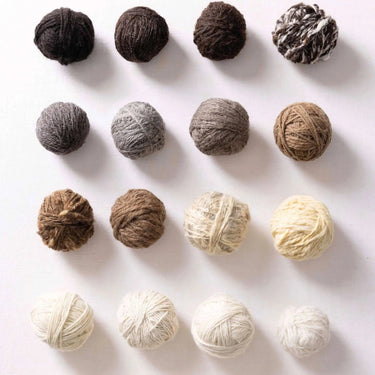 Variety of yarn balls showcasing British sheep breeds for "A Knitter's Guide" to pure wool. Natural fibers in diverse shades.