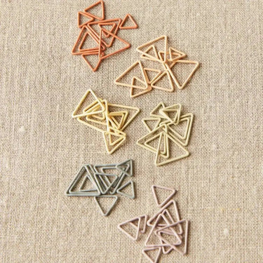 Triangle Stitch Markers by Cocoknits in earth tone colors on a beige background.