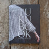 Cover of Tukubook highlighting Nordic knits with a textured sweater on wooden background.