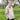 Woman wearing a beige knitted sweater in a grassy outdoor setting. Tukubook knitting book