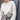 Person wearing a white knitted sweater from the Tukubook collection, showcasing Finnish knitting design with subtle textures. Tukubook knitting book