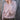 Woman wearing a light pink knitted sweater against a wooden background. Tukubook knitting book