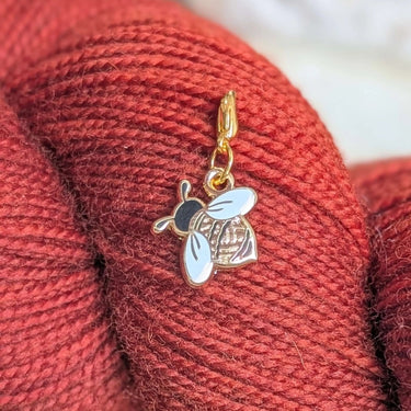 Gold and white bee charm on red yarn, Twill + Print Progress Keepers for knitting and crochet projects.