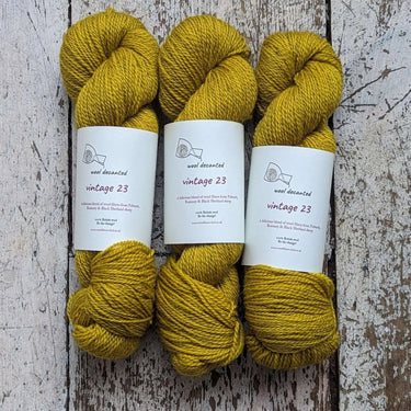 Wool Decanted Vintage 23 4ply Yarn skeins in mustard yellow on rustic wood background