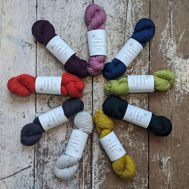 Colorful skeins of Wool Decanted vintage 23 4ply yarn displayed on a rustic wooden surface, showcasing vibrant shades and textures.